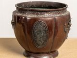 a large bronze pot sitting on top of a wooden table