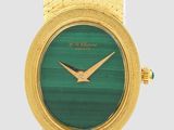 une image montrant un gros plan d'une montre-bracelet en or avec un cadran vert