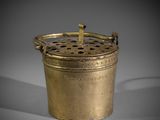 an old brass pot with a handle on a grey background