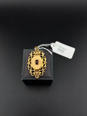 a close up of a gold plated pendant on a black surface