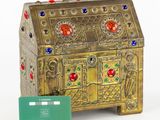 a gold chest with a green card next to it