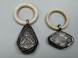 two pieces of silver and ivory jewelry on a white surface