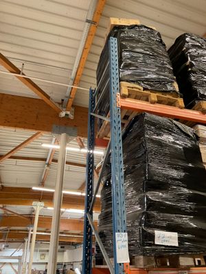 une grande pile de sacs noirs posée sur une étagère dans un entrepôt