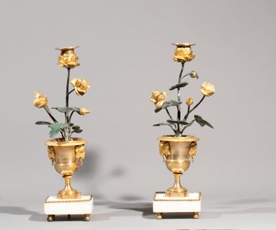 une paire de vases en or ornés de roses, posés sur des socles en marbre, sur une table