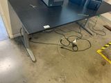 une table noire sur laquelle se trouvent deux ordinateurs, dans une pièce