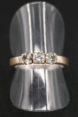 gros plan d'une bague en or ornée de trois diamants