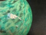 a green vase sitting on a table with a black background