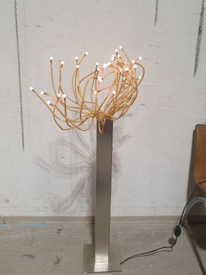 a tall metal vase with a bunch of flowers in it