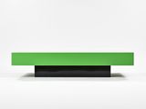 a green bench sitting on top of a white surface