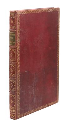 un vieux livre à la couverture rouge posé sur une surface blanche