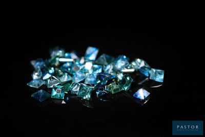un gros plan sur un tas de diamants bleus posés sur une surface noire