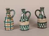 three green and white vases sitting next to each other on a table