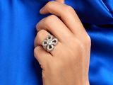 woman ' s hand holding a diamond ring with a blue silk background