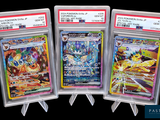 Trois cartes Pokémon différentes sont exposées dans des pochettes en plastique.