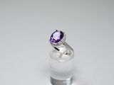a close up of a ring with a purple stone on top of a glass