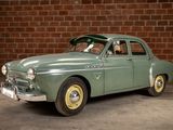 a green car that is parked in front of a brick wall