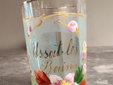 a glass with a flower on it sitting on a table