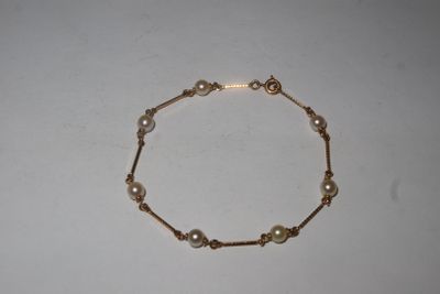 a close up of a bracelet with pearls on a white surface
