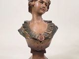 statue d'une femme en robe, posée sur un socle, avec un fond blanc