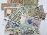 une pile de billets de différentes devises posée sur une surface blanche
