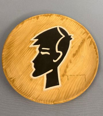 une assiette en bois sur laquelle est dessiné le visage d'un homme