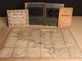 trois livres posés sur une table sur laquelle se trouve une carte