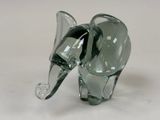 une figurine d'éléphant en verre posée sur une surface blanche