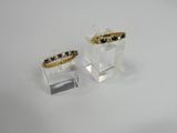 pair of gold and garnett rings on clear acrylic stand