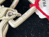 a silver metal cross with a red string around it