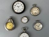 Plusieurs types de montres de poche sont exposés sur un support gris.