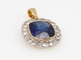 a close up of a blue sapphire and diamond pendant on a white background