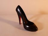 des chaussures à talons hauts noires aux semelles rouges posées sur une surface blanche