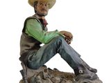statue d'un homme assis sur un rocher, coiffé d'un chapeau de cow-boy