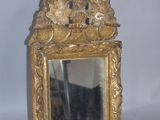 a small mirror with a gold frame on a white background