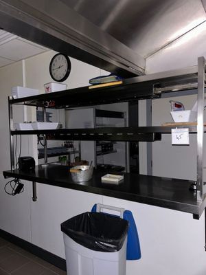 a kitchen with a clock on the wall and a trash can on the floor
