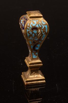 un vase bleu et or posé sur une surface noire