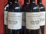 trois bouteilles de vin rouge sont alignées sur une surface rouge