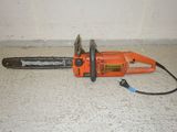 an orange chainsaw sitting on the floor next to a white wall