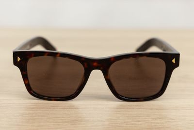 sunglasses on a wooden table with a white wall in the background