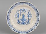 une assiette ancienne bleue et blanche représentant un homme et une femme dans un jardin