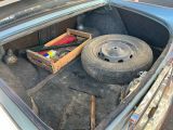 le coffre d'une voiture contenant un pneu et des outils