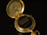 a gold pocket watch sitting on a black surface