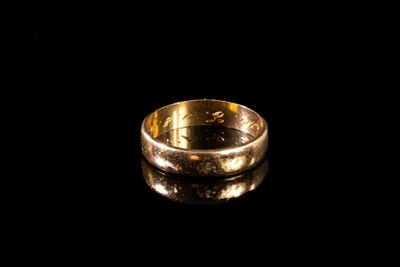 gros plan d'une bague en or sur une surface noire