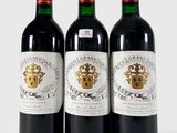 trois bouteilles de vin rouge posées sur une table blanche