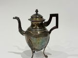 an antique teapot with a handle and a handle on a stand