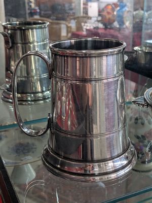 deux tasses en argent posées sur une table en verre