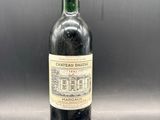 une bouteille de vin rouge avec un bouchon rouge posée sur une table