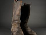 an old pair of brown leather boots on a black background