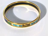 un gros plan d'un bracelet en or orné de pierres bleues et vertes