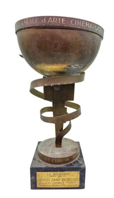 une image représentant un bol en métal orné d'un motif en spirale, posé sur un socle en bois